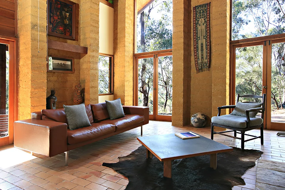 Sunlit living room with handcrafted timber and mud-brick walls